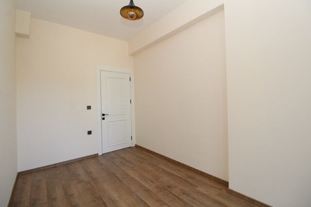 Empty room with white walls, wooden floor, and ceiling light fixture in Yalova property.