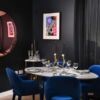 Elegant dining area featuring a stylish table, blue velvet chairs, and contemporary artwork. Perfect.