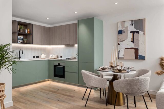 Bright contemporary kitchen with green cabinetry and a cozy dining space in Southall, London.