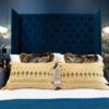 Elegant bedroom featuring a plush blue headboard, decorative pillows, and modern lighting fixtures.