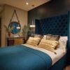 Elegant bedroom with a plush blue headboard and modern decor.