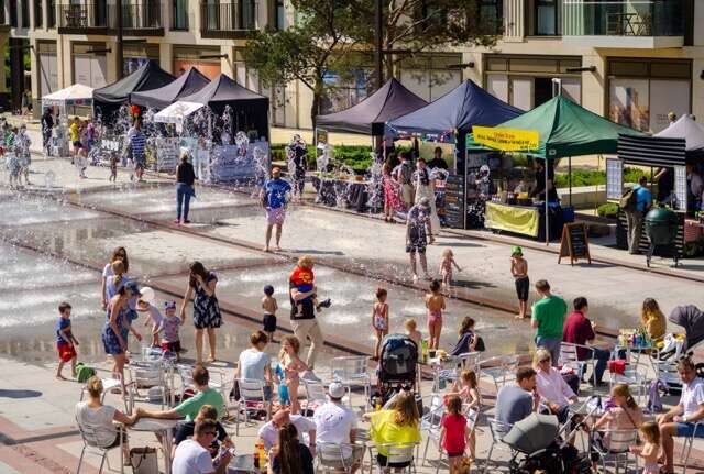Colorful outdoor market with families enjoying a sunny day in Wapping.