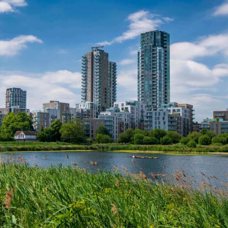 Bright modern high-rise buildings near Wandsworth green spaces and river in London.