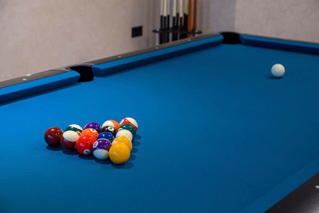 Pool table with balls set up for a game in a contemporary living space.