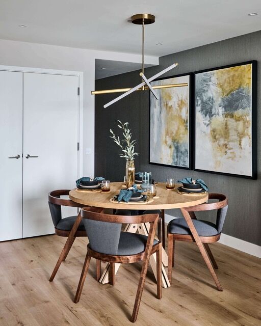Contemporary dining area featuring a round wooden table, elegant chairs, and abstract wall art in a.