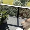 Balcony overlooking lush green garden with trees and outdoor seating, ideal for relaxing and enjoyin.