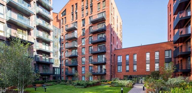 Modern apartment buildings in Birmingham with balconies and green outdoor spaces.