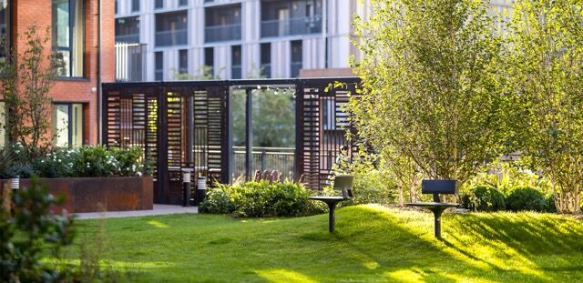 Modern Birmingham apartment complex with landscaped gardens and outdoor seating areas.