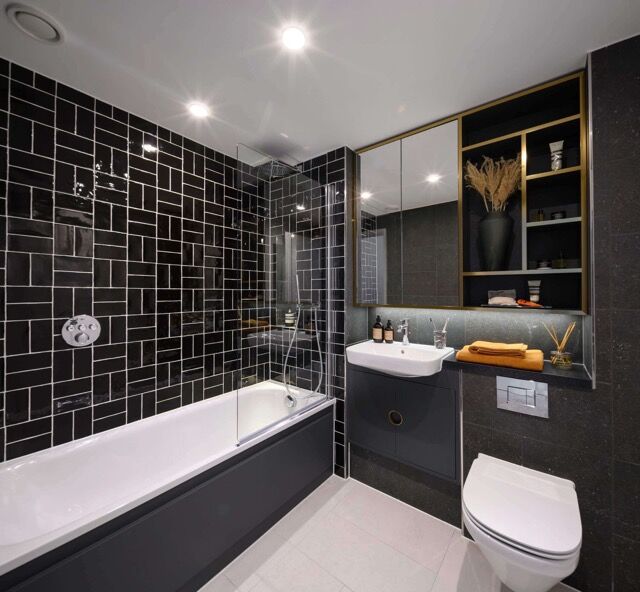 Bright 1-bedroom apartment bathroom with black tiles and sleek fixtures in London.