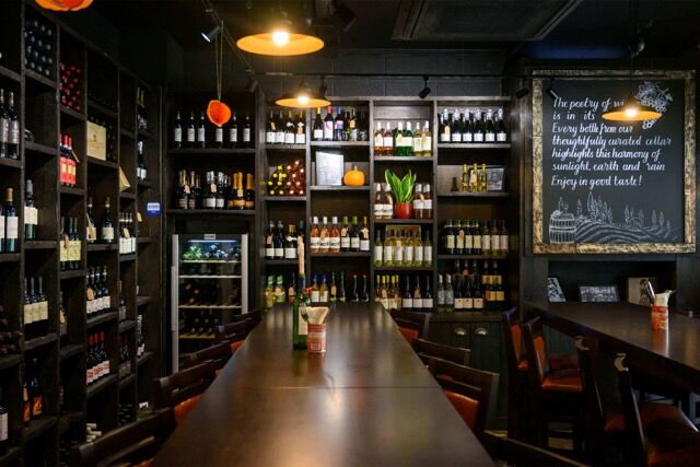 Cozy wine bar with shelves of wine bottles and a chalkboard menu in Woolwich, London.