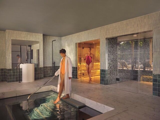 Relaxing spa scene with a woman enjoying the hot tub indoors, overlooking the river.