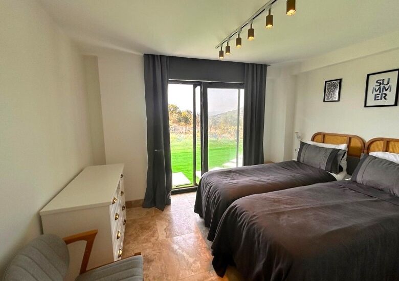 Bright bedroom with large glass doors opening to a private balcony and scenic views in Bodrum.