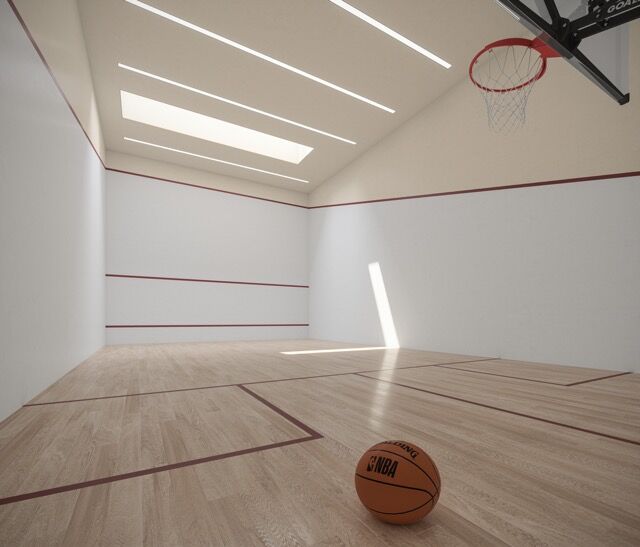 Indoor basketball court with high ceilings, natural light, and a basketball on the floor.