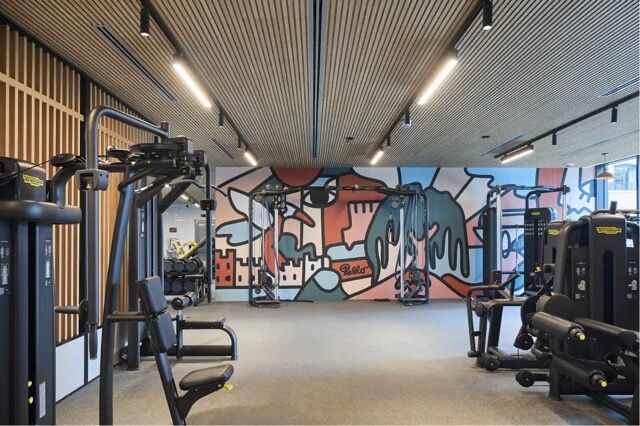 Gym interior with modern fitness equipment and vibrant wall art in West London.