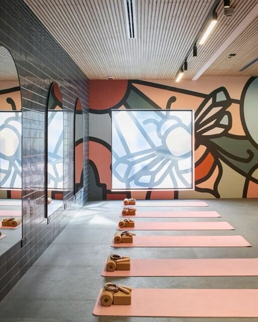 Yoga studio interior with vibrant wall art, mirrors, and neatly arranged mats for practice.