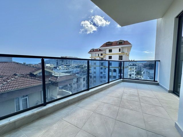 Bright balcony view of cityscape from modern 1+1 apartment with pool access.