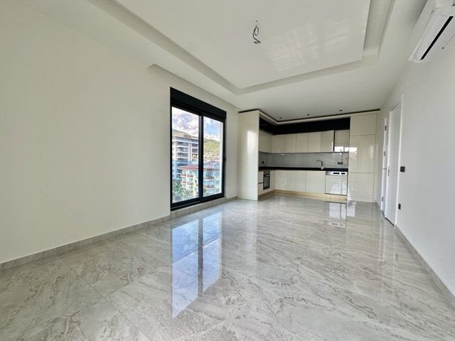 Spacious modern 2+1 apartment with open-plan living area and large windows in Alanya Guller Pınarı.