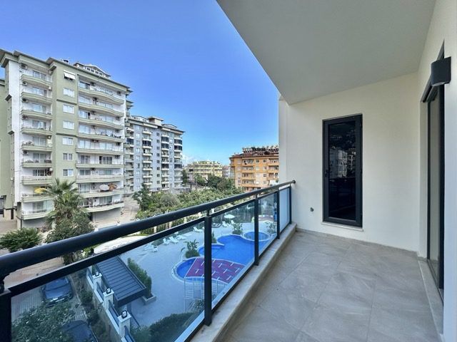Spacious balcony view of Alanya city and pool area from a modern 2+1 apartment. Prime location near.