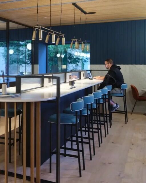 Contemporary café interior featuring a long bar, blue accents, and large windows offering scenic riv.