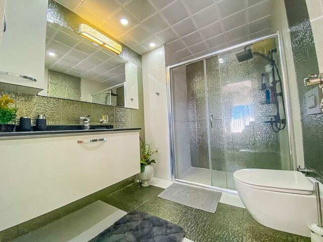 Bright bathroom featuring a glass-enclosed shower, white fixtures, and contemporary design in a spac.