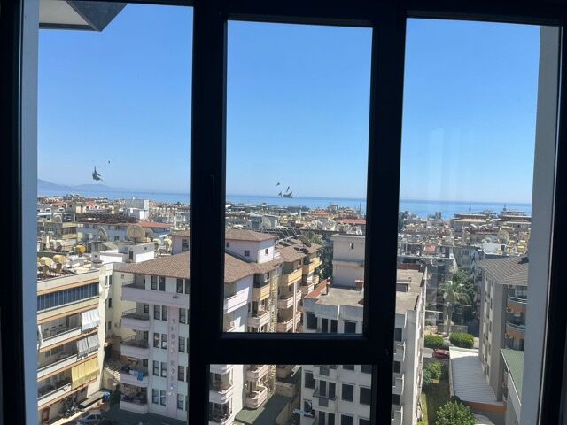 Sea view from a modern 1-bedroom apartment in Alanya, featuring full amenities and cityscape surroun.