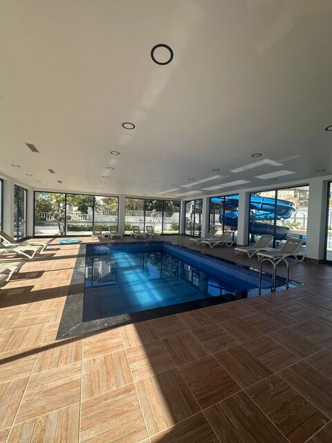 Indoor swimming pool with large windows and natural light.