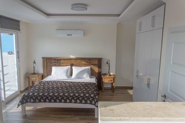 Furnished 4-bedroom villa interior with garden and pool view in Fethiye, Turkey. Modern bedroom with.