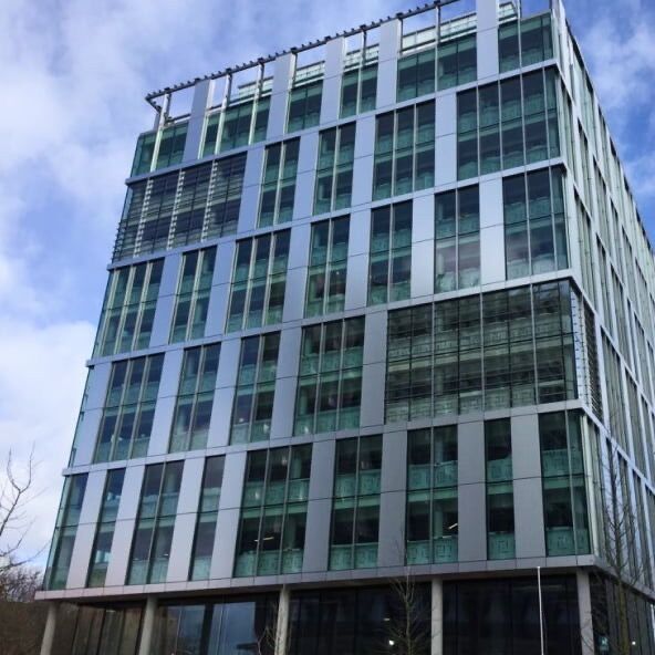 Modern glass-fronted building in West London, offering luxury riverside residences with vibrant city.