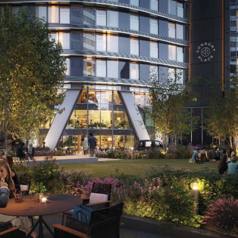 Modern waterfront building in Canary Wharf with outdoor seating and lush landscaping.