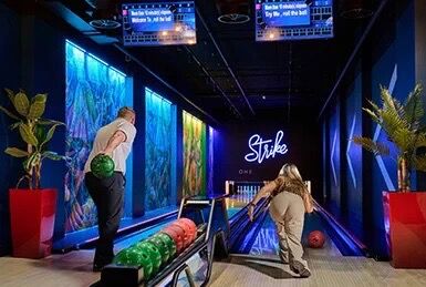 Bright indoor bowling alley with scenic waterside views and vibrant lighting.