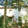 Beautiful Tuscan-style house surrounded by lush greenery and tall trees.