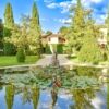 Beautiful view of a luxurious property in Umbria with landscaped gardens and a pond.