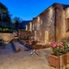 Toscana villa with stone exterior, outdoor seating, and lush garden views for sale. Perfect for luxu.