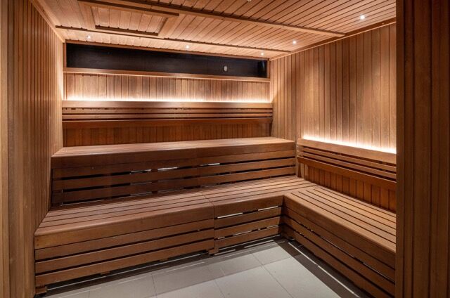 Sauna room with wooden benches in Riverside Apartments for relaxation and wellness.