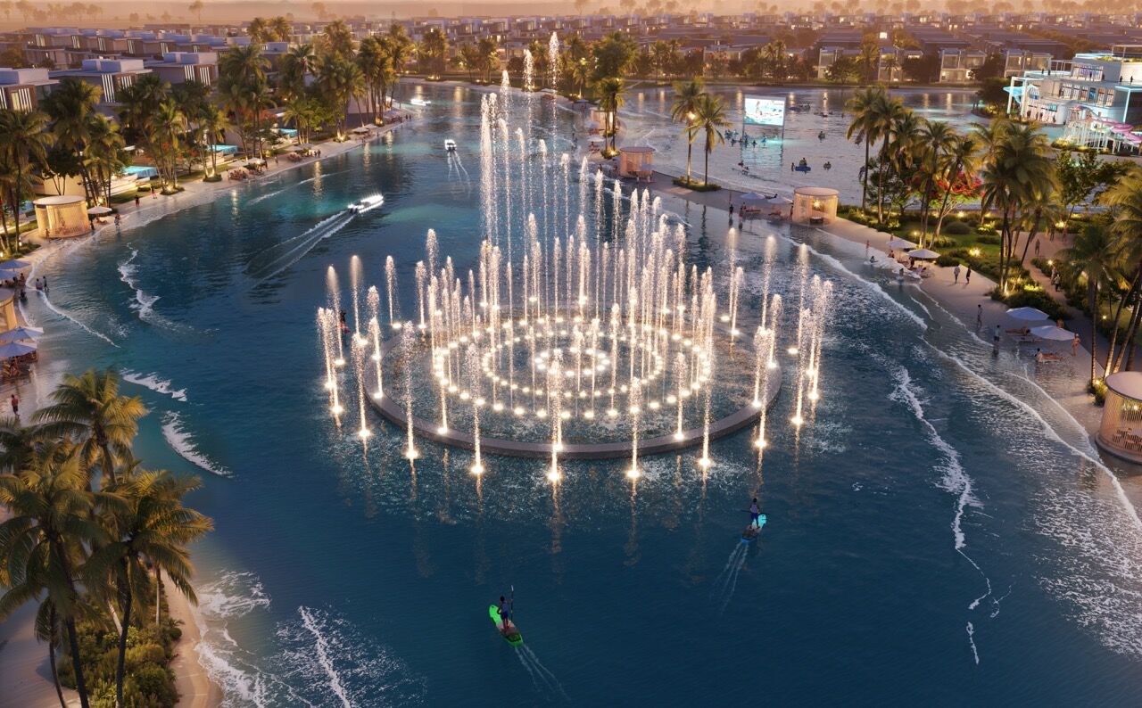 Dubai fountain illuminated at sunset with water jets and palm trees in the background.