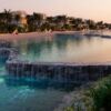 Elegant pool with waterfalls and lush tropical plants in Dubai resort setting.
