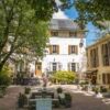 Elegant stone-walled estate with gated entrance, main house, and four charming gites on a lush 2768.