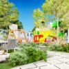 Modern seaside garden with colorful children's play equipment and lush greenery.