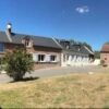 Traditional farmhouse with brick exterior and surrounding garden in Macquigny, France.