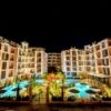 Luxury apartment complex with illuminated pools and gardens at night.