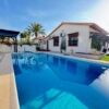 Poolside view of a contemporary villa in Cabo Roig with a private swimming pool and lush garden.