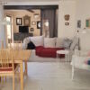 Cozy living room with a large sofa, dining area, and decorative wall art in a lively seaside town.