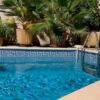 Small village house with heated pool, lush plants, and outdoor terrace.