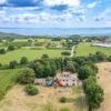 Aerial view of a luxury villa surrounded by lush green fields in Tuscia, Viterbese.