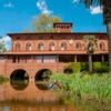 Historic waterfront villa with lush greenery and water reflections, inspired by the birthplace of mu.