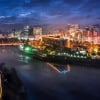Bright cityscape of Dhaka with illuminated buildings and river views at dusk.