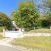 Beautiful countryside home with a white gate, surrounded by trees and a stone wall in Marcillac-la-C.