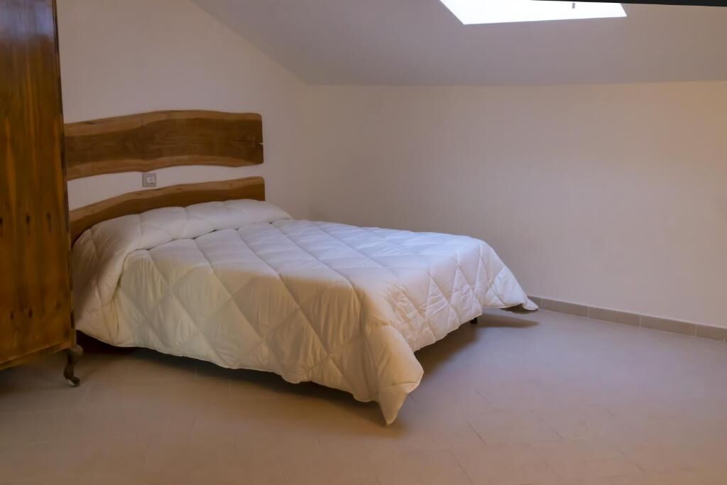 Modern bedroom with wooden bed frame and white bedding. Spacious bedroom featuring a wooden bed frame and bright, clean decor.