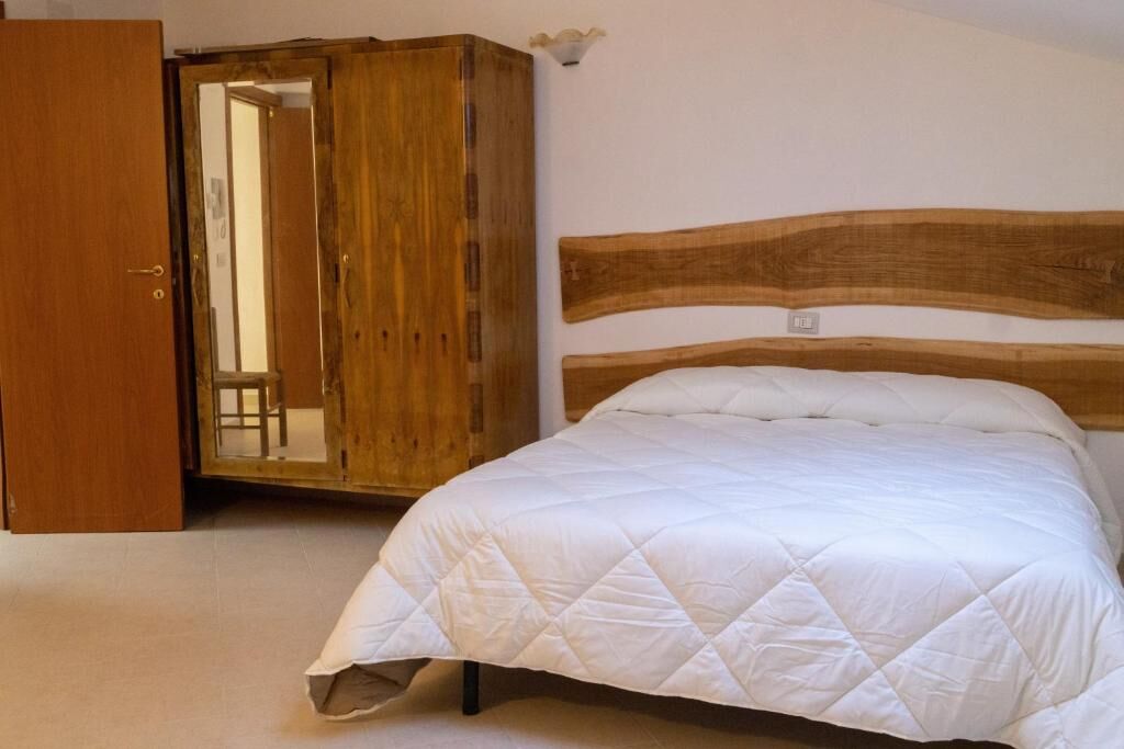 Elegant 5-Bed House for Sale in Sepino Spacious bedroom with a large bed and wooden accents in Sepino property listing.