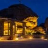 Night view of Lithos Cave Villa with outdoor lighting in Agrari, Mykonos.